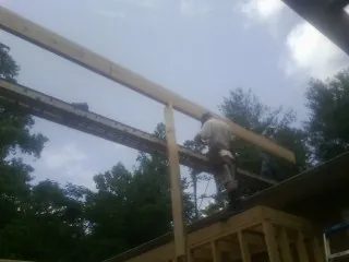 Carpenter setting a ridge beam over a new addition frame — Ice Dam Removal by Roofing Brothers in Hill Afb