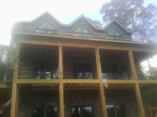 Dormers and porch framing on a large log home under construction — Roof Coating work by our crew in Hill Afb