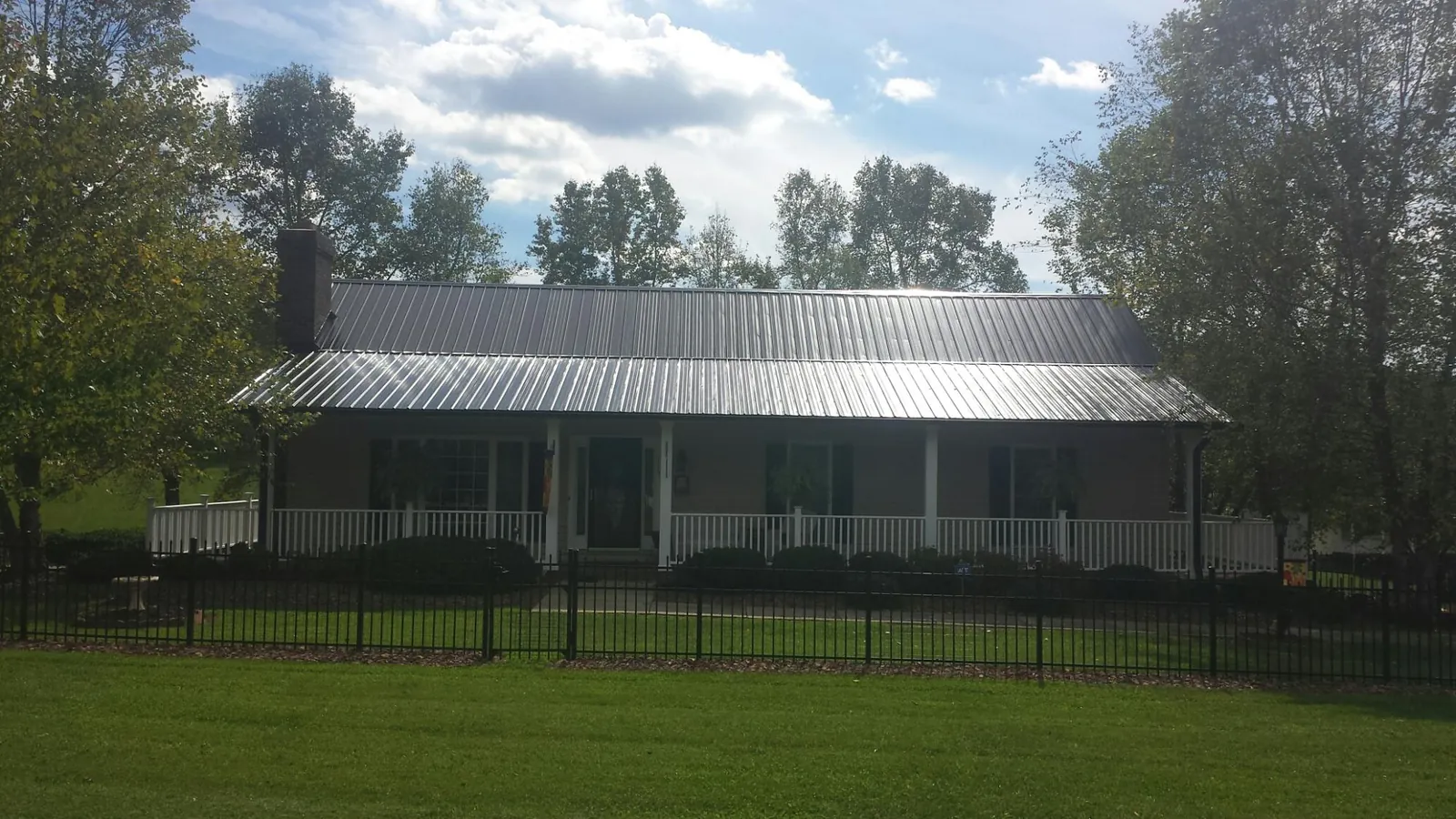 Gray metal roof on a brick ranch with a full width front porch — Gutter Guard Installation work by our crew in Hill Afb