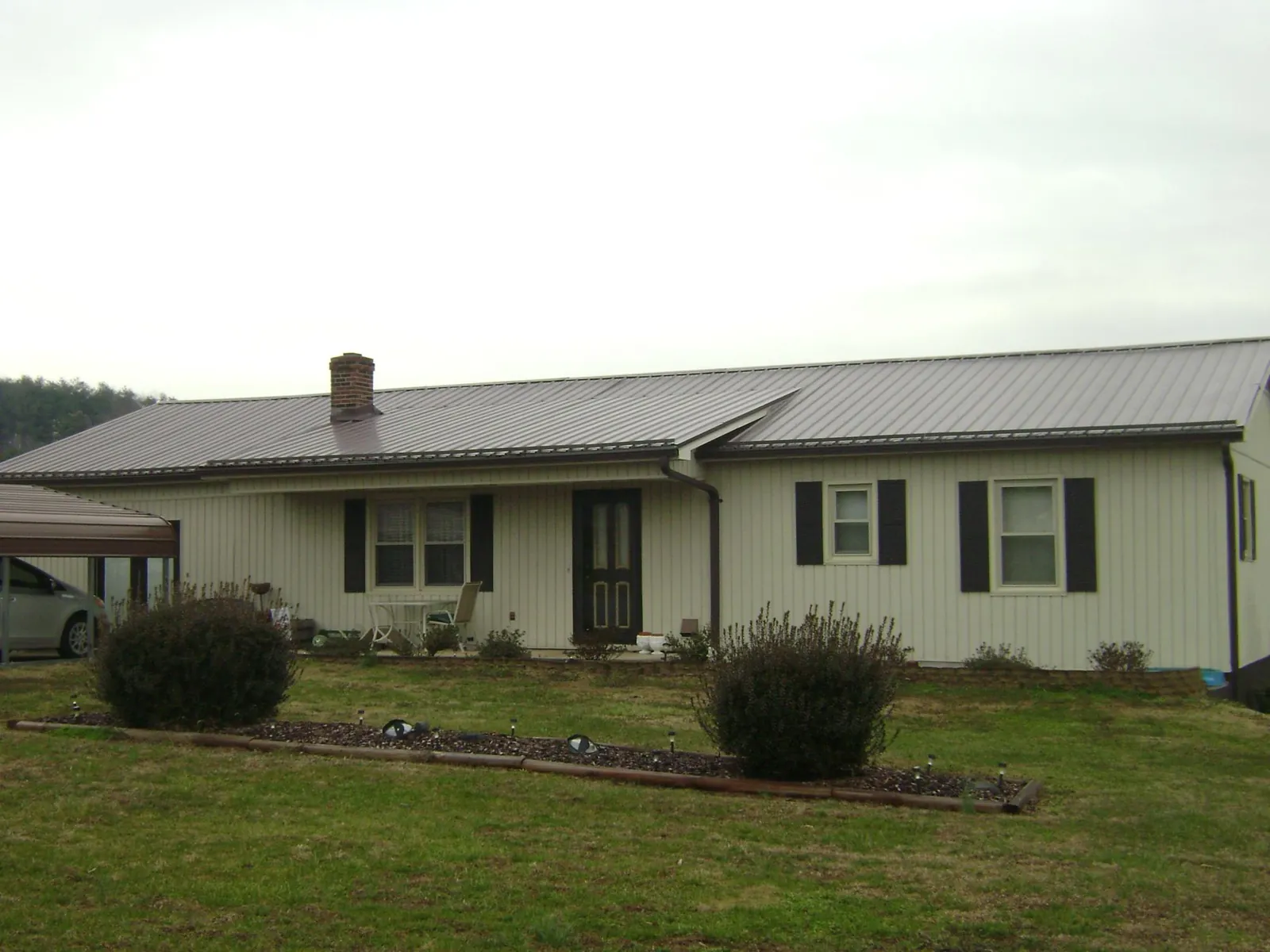 Brown metal roof on a cream sided ranch home with a brick chimney in Hill Afb