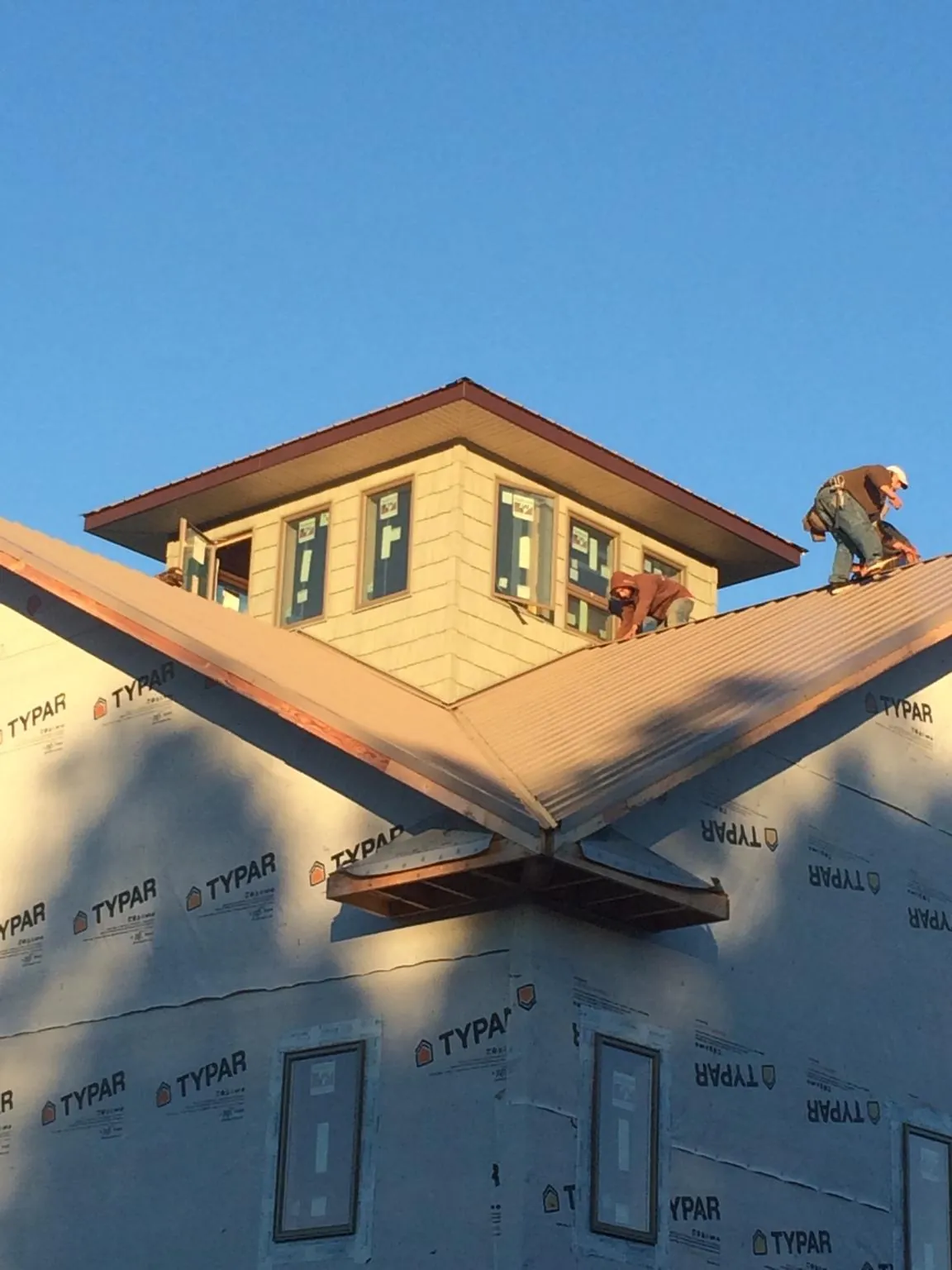 Roofers working around a rooftop cupola on a new metal roof at sunset — Roof Waterproofing in Hill Afb by Roofing Brothers